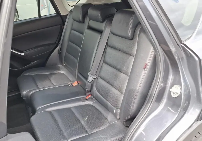 Vue intérieure côté droit sur les sièges arrière en cuir noir du Mazda CX-5 gris 2015 avec porte ouverte.