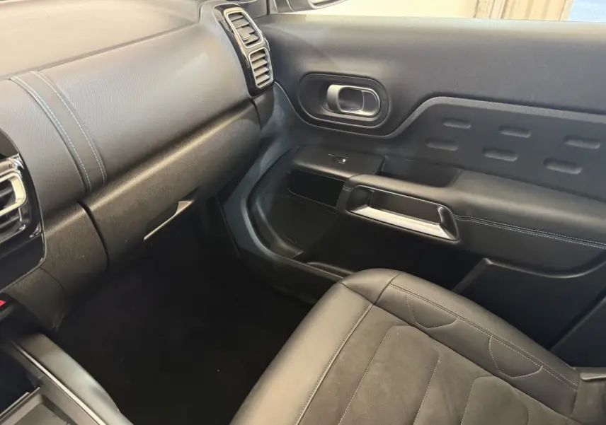 Vue intérieure côté passager avant du Citroën C5 Aircross gris clair, montrant siège et panneau de porte noirs.