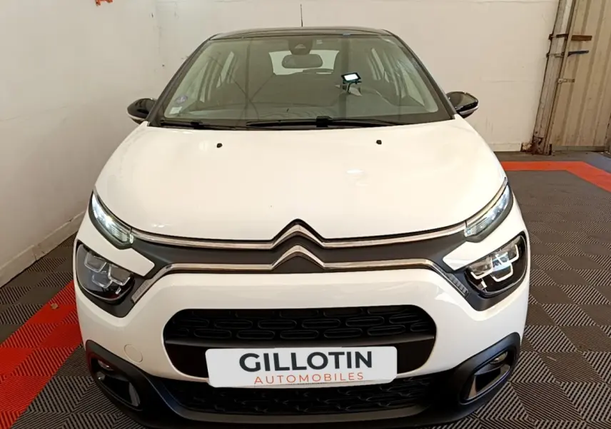 Vue avant d'une Citroën C3 blanche 2021 avec phares LED et calandre noire dans un showroom.