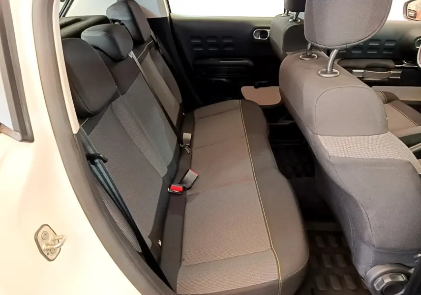 Vue intérieure côté gauche montrant la banquette arrière grise et les sièges avant d'une Citroën C3 blanche 2021.