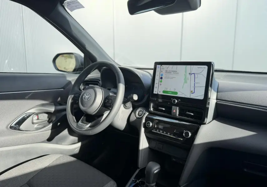 Vue intérieure côté conducteur de la Toyota Yaris Cross 2026, avec écran tactile GPS et volant multifonctions en cuir.
