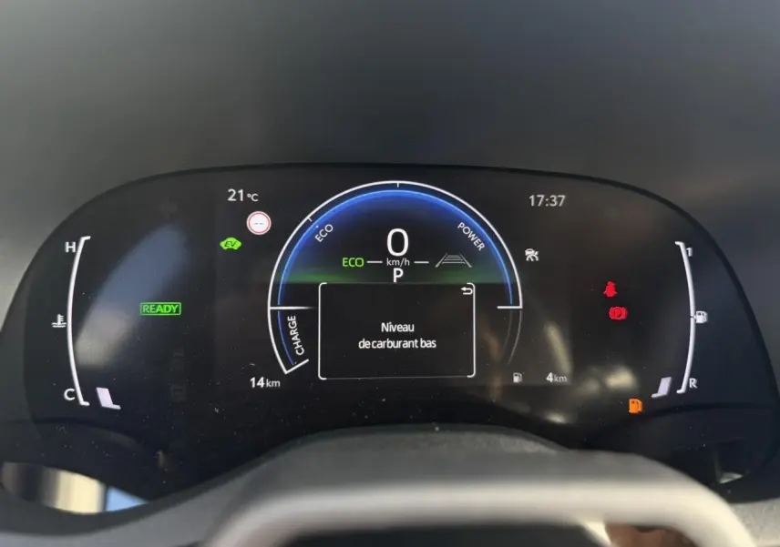 Vue rapprochée du tableau de bord numérique de la Toyota Yaris Cross 2026 affichant un avertissement de niveau de carburant bas.