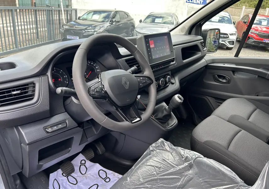 Intérieur du Renault Trafic Fourgon 2025 vu côté conducteur, montrant le volant multifonction et la console centrale avec écran tactile.
