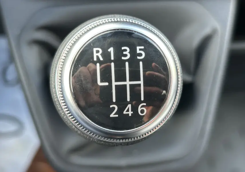 Gros plan sur le pommeau de la boîte manuelle du Renault Trafic Fourgon L1H1, avec marquage des vitesses en blanc.