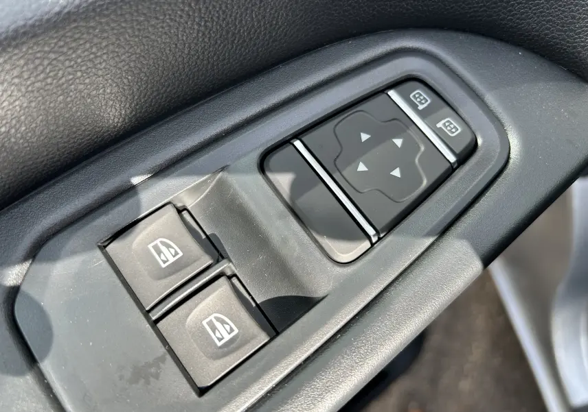 Gros plan sur les commandes électriques des vitres et des rétroviseurs du Renault Trafic Fourgon gris Highland.