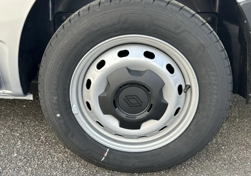 Gros plan sur la roue avant gauche du Renault Trafic Fourgon gris Highland, avec jante acier et logo Renault central.