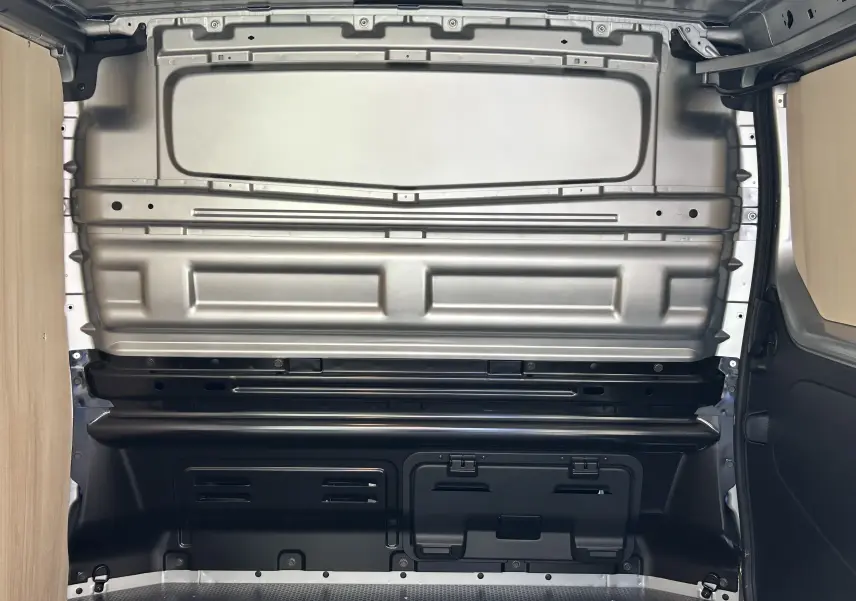 Intérieur du fourgon Renault Trafic L1H1 Advance 2025 montrant la cloison métallique grise et les panneaux bois latéraux.