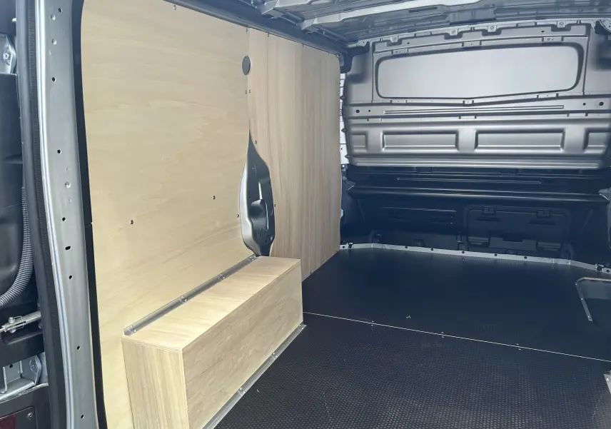 Intérieur du Renault Trafic Fourgon L1H1 gris Highland, vue latérale droite montrant le kit bois de protection et rangement.
