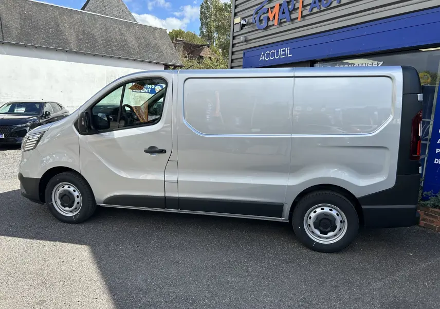 Profil droit du Renault Trafic Fourgon gris Highland 2025, avec porte latérale coulissante et jantes acier simples.