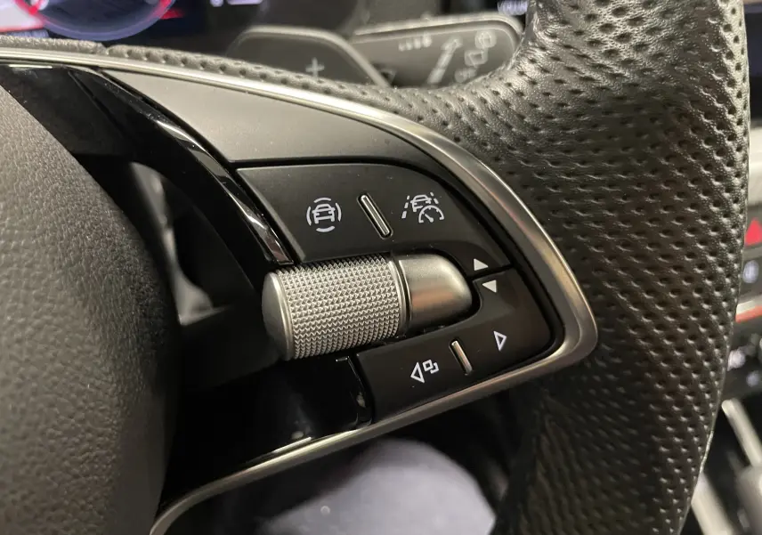 Gros plan sur les commandes de régulateur de vitesse au volant perforé d'une Skoda Scala 2025.