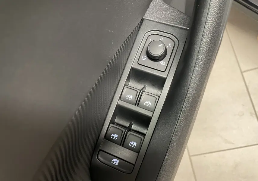 Gros plan sur les commandes de réglage des rétroviseurs et des vitres côté conducteur de la Skoda Scala 1.5 TSI 150 DSG7 Monte-Carlo noire.