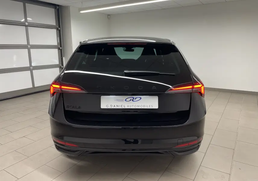 Vue arrière d'une Skoda Scala 1.5 TSI 150 DSG7 Monte-Carlo en noir Magic avec feux LED allumés en intérieur.