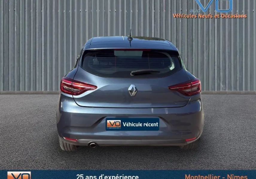 Vue arrière d'une Renault Clio gris métallisé 2022 avec feux LED et logo centré sur un fond industriel.