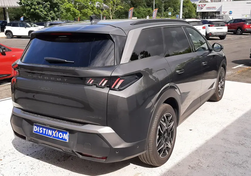 Vue 3/4 arrière droite du Peugeot 5008 Hybrid gris titane métal avec vitres teintées et jantes alliage noires.