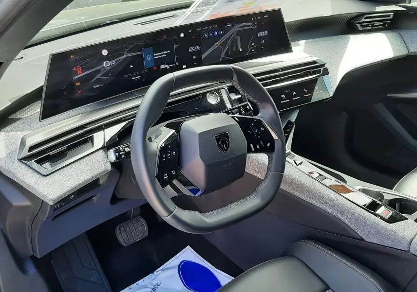 Vue intérieure côté conducteur du Peugeot 5008 Hybrid 145ch Allure 2025, tableau de bord gris titane avec écran numérique panoramique.