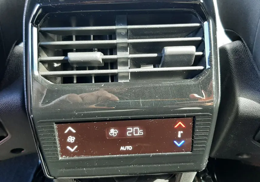 Vue rapprochée de la sortie d’air arrière et du panneau de contrôle de la climatisation digitale du Peugeot 5008 gris titane.