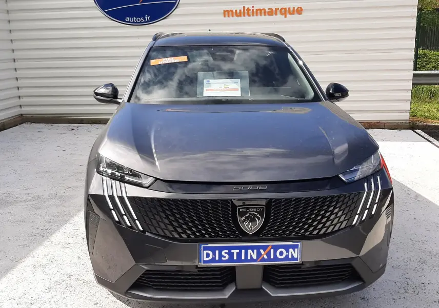 Vue avant d'un Peugeot 5008 Hybrid gris titane métal, avec calandre noire et feux LED verticaux distinctifs.