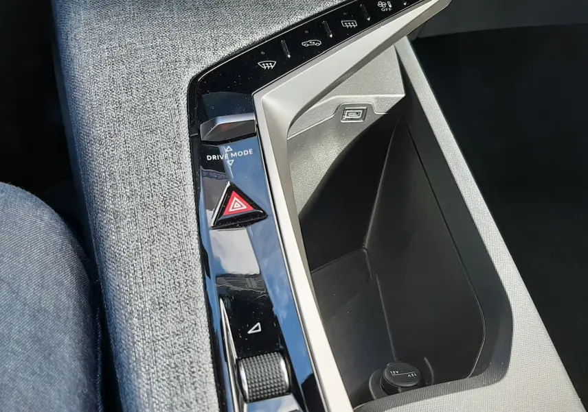 Vue rapprochée de la console centrale grise tissu du Peugeot 5008 Hybrid 2025 avec commandes tactiles et prise USB visible.