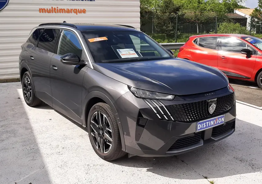 Peugeot 5008 Hybrid gris titane métal en 3/4 avant droit, avec calandre noire distinctive et jantes alliage bicolores.
