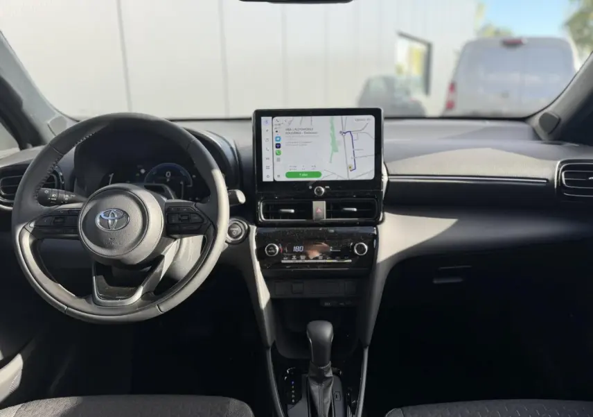 Vue intérieure avant de la Toyota Yaris Cross 1.5 Hybrid 130 BVA Design, tableau de bord noir avec écran tactile GPS et volant multifonctions.