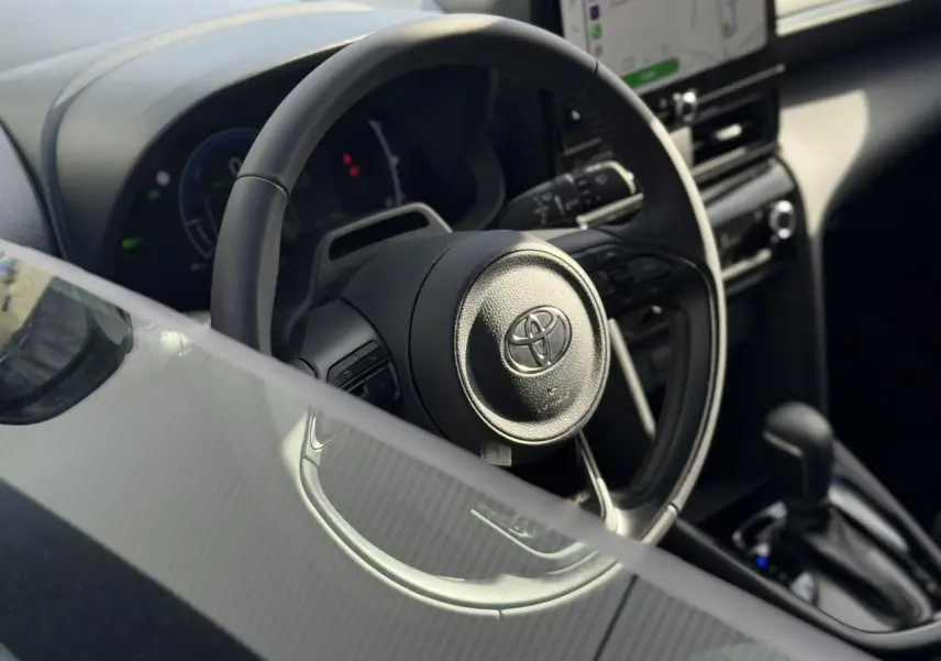 Vue rapprochée du volant en cuir et du tableau de bord numérique de la Toyota Yaris Cross 2026, intérieur noir.