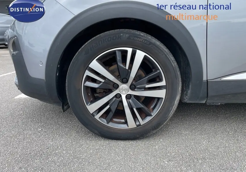 Gros plan sur la roue avant droite du Peugeot 3008 gris Artense métal, avec jante alliage bicolore distinctive.