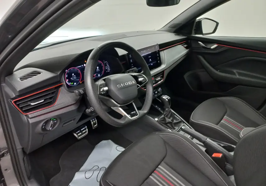 Intérieur côté conducteur du Skoda Scala 2025 gris graphite, avec tableau de bord moderne et éclairage rouge subtil.