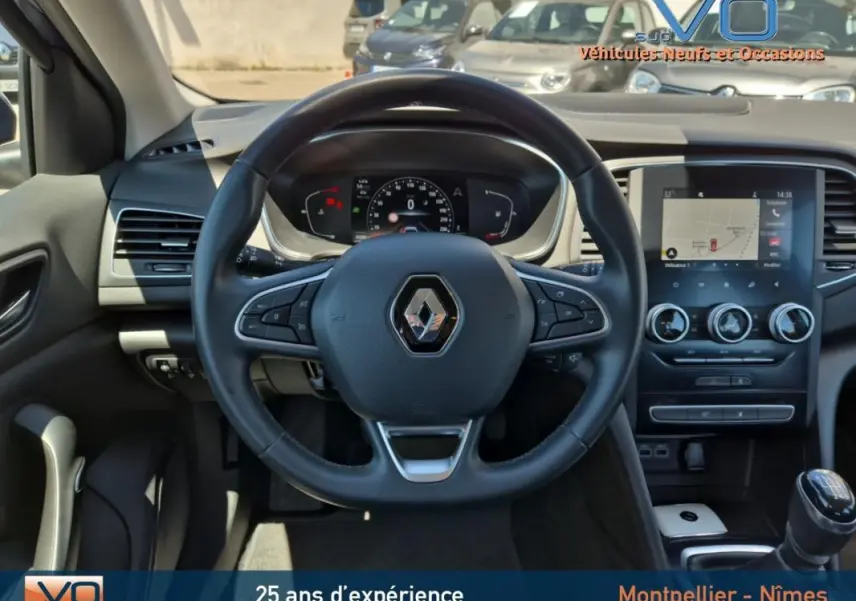 Vue centrée sur le volant et tableau de bord de la Renault Mégane IV Business, avec écran tactile et levier de vitesse manuel.