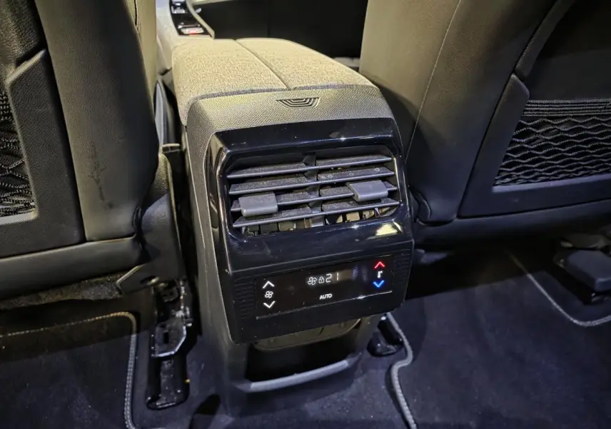 Vue rapprochée de la console centrale arrière du Peugeot 5008 gris, avec commandes de climatisation et aérateurs noirs.