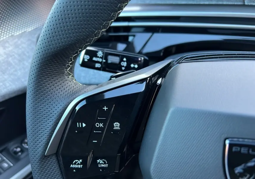 Gros plan sur le volant cuir perforé du Peugeot 3008 Hybrid 145 GT, avec commandes multifonctions noires brillantes.