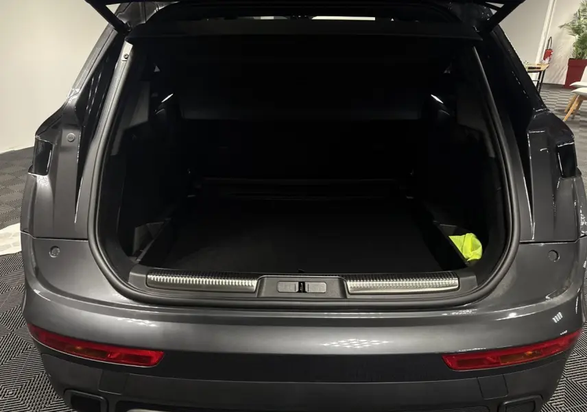 Vue arrière du coffre ouvert d’un DS7 Crossback gris métallisé, montrant l’espace de chargement et le pare-chocs avec feux rouges.