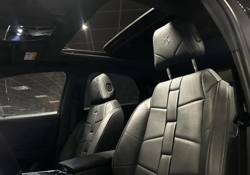 Vue intérieure des sièges avant en cuir noir avec logo DS embossé et toit ouvrant panoramique du DS7 Crossback 2025.