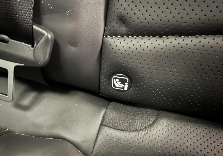 Gros plan sur la fixation ISOFIX sur la banquette arrière en cuir noir perforé du DS7 Crossback gris.