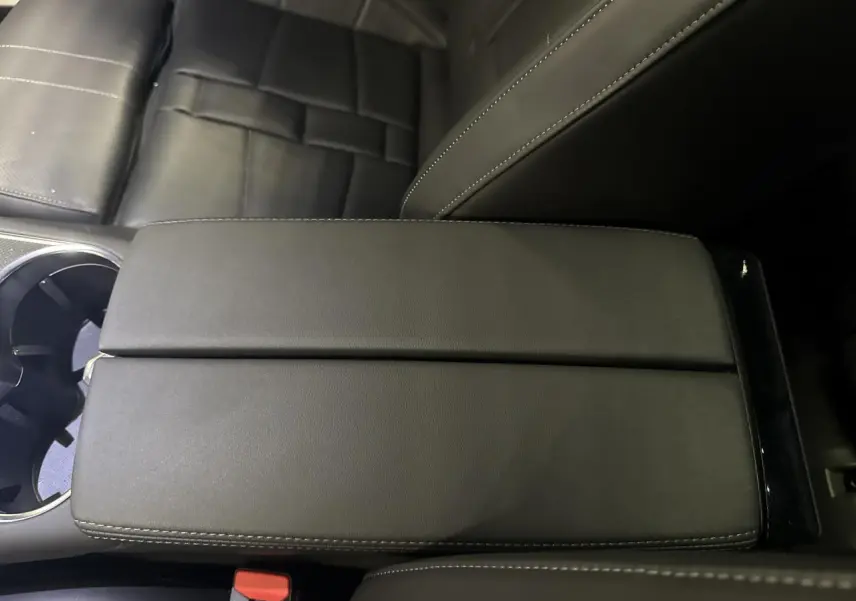 Gros plan sur l'accoudoir central en cuir noir du DS7 Crossback 2025, avec siège et porte-gobelets visibles.