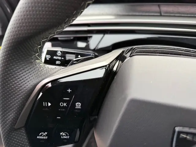 Gros plan sur le volant cuir multifonction noir avec commandes intégrées du Peugeot 3008 Hybrid 145 GT.