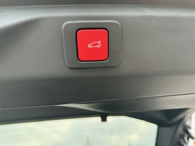 Bouton rouge de commande du hayon motorisé sur le coffre intérieur du Peugeot 3008 Hybrid 145 gris titane.