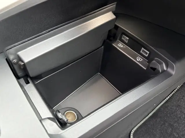 Gros plan sur la console centrale ouverte du Peugeot 3008 Hybrid 145 GT, montrant prises USB et prise 12V intégrées.