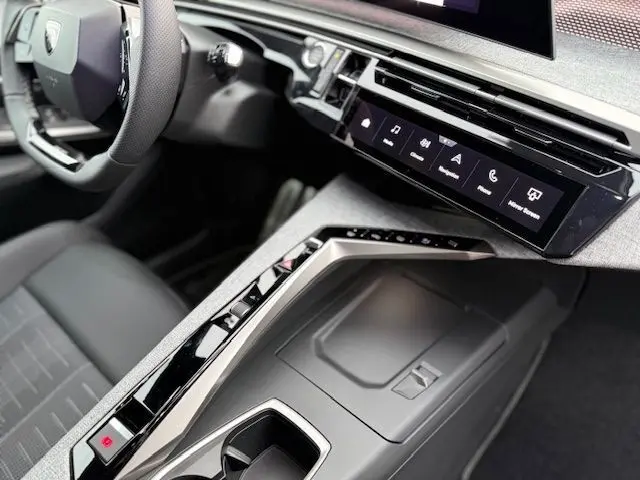 Vue intérieure rapprochée du poste de conduite du Peugeot 3008 Hybrid 145 GT, avec écran tactile panoramique et volant cuir multifonction.