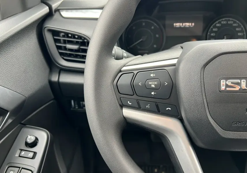 Vue rapprochée du volant multifonctions gris foncé de l'Isuzu D-MAX 2026 avec commandes audio et téléphone intégrées.