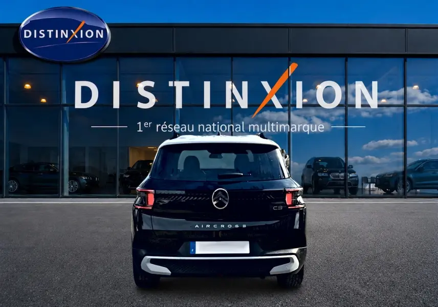 Vue arrière d'un Citroën C3 Aircross noir 2026, avec toit blanc et feux arrière LED distinctifs, devant une vitrine Distinxion.