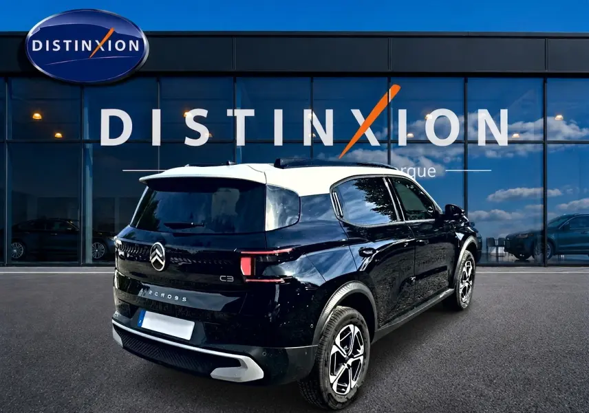 Vue 3/4 arrière droite d'une Citroën C3 Aircross 2026 noire avec toit blanc et jantes alu distinctives.