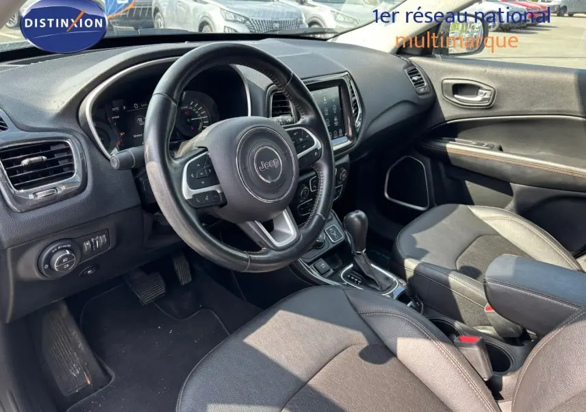 Intérieur du Jeep Compass 2021 hybride rechargeable, vue côté conducteur sur le tableau de bord et sièges en cuir noir.