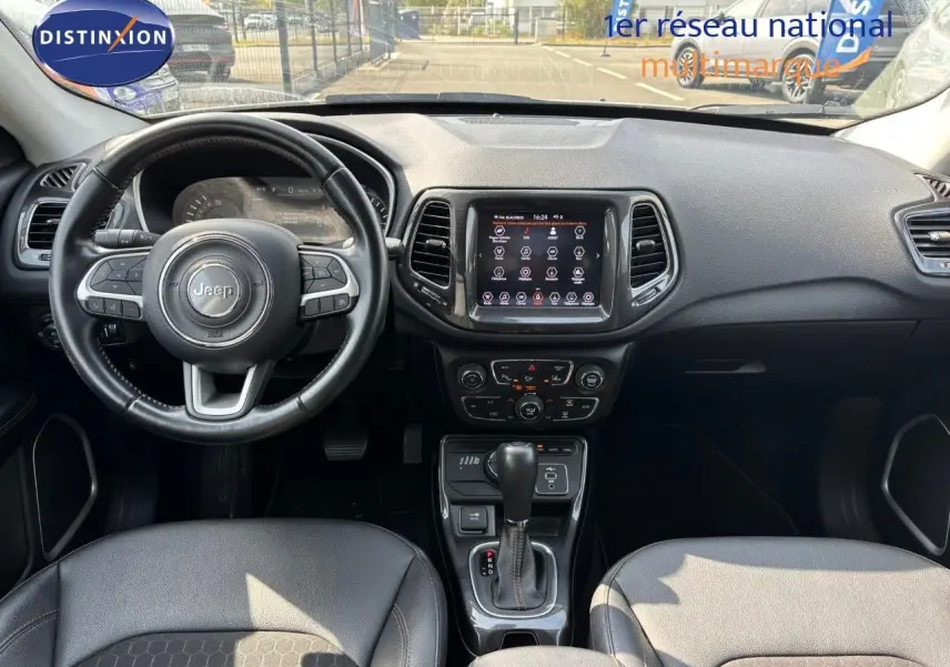 Vue intérieure avant du Jeep Compass hybride rechargeable 2021, tableau de bord et volant en cuir noir visibles.