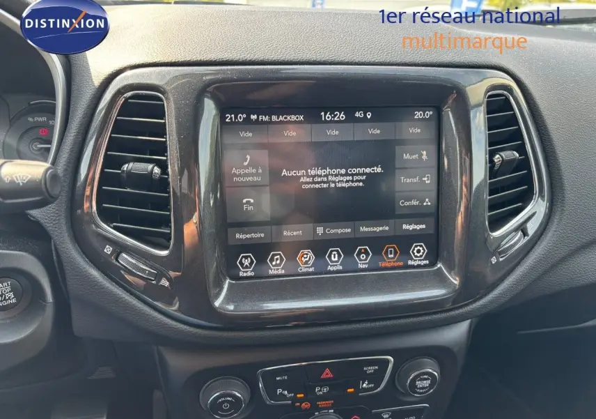 Écran tactile central du tableau de bord du Jeep Compass blanc, affichant le menu téléphone et climatisation.