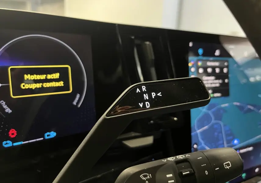 Gros plan sur la commande de boîte automatique dans l'habitacle du Renault Austral blanc, avec tableau de bord numérique en arrière-plan.