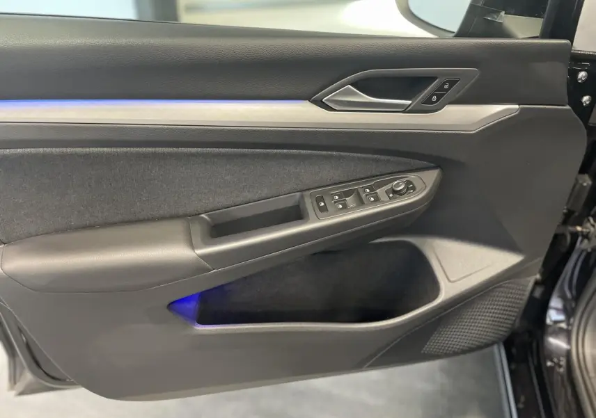 Panneau de porte avant gauche noir de Volkswagen Golf 1.5 eTSI 2024 avec éclairage d'ambiance bleu et commandes électriques.