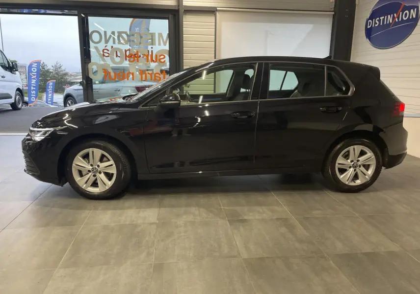 Profil côté gauche d'une Volkswagen Golf 1.5 eTSI Style noire, avec jantes alliage 17 pouces Nottingham, en intérieur showroom.