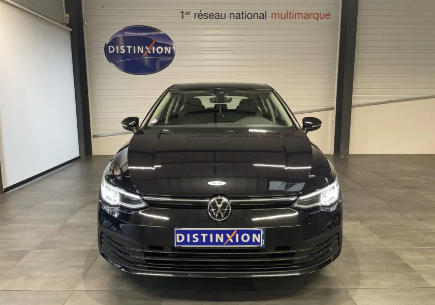 Volkswagen Golf 2024 noire vue de face avec phares LED allumés dans un showroom intérieur.