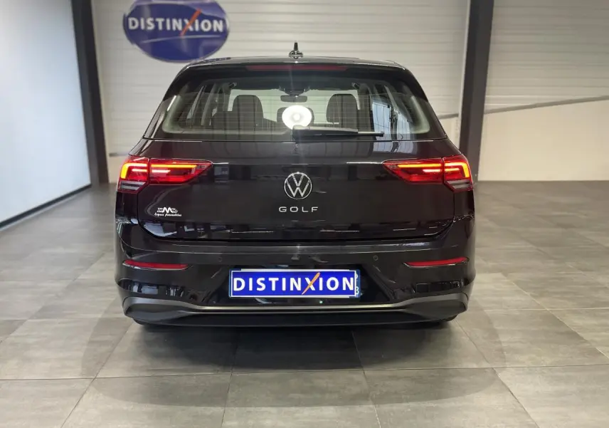 Vue arrière d'une Volkswagen Golf 1.5 eTSI noire 2024 avec feux LED allumés dans un showroom.