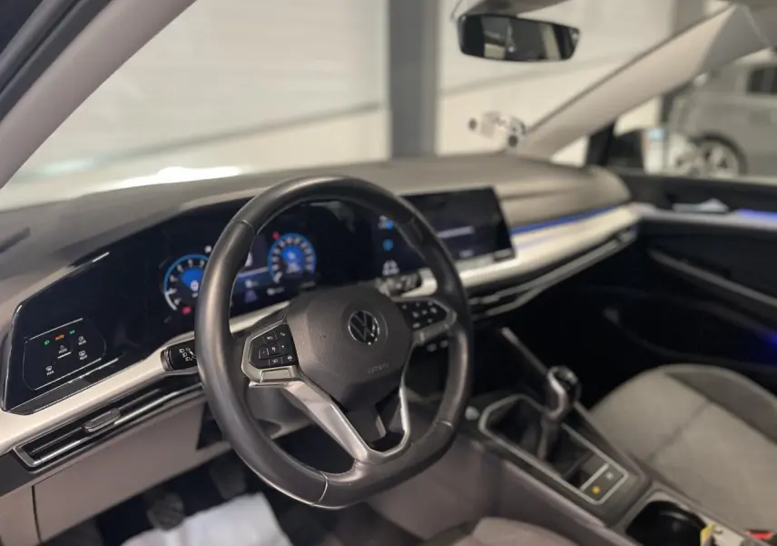 Intérieur de la Volkswagen Golf 1.5 eTSI 2024, vue du poste de conduite avec volant cuir et tableau de bord digital.